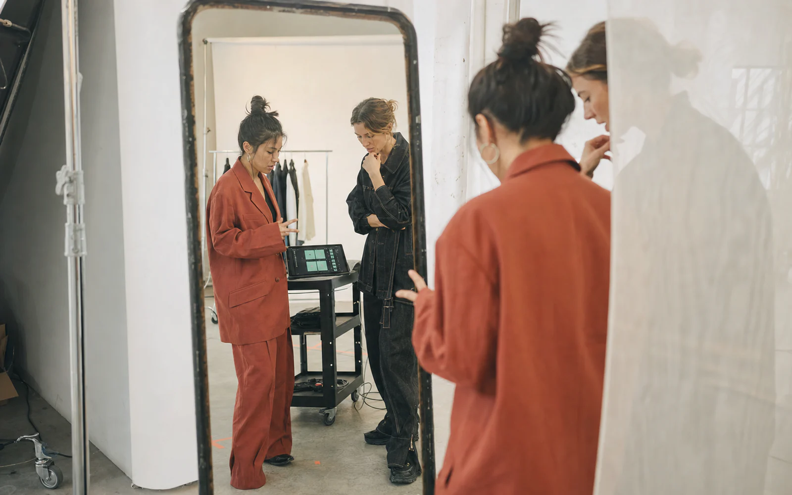 Two adult women discussing a campaign around a tablet as seen through a studio mirror